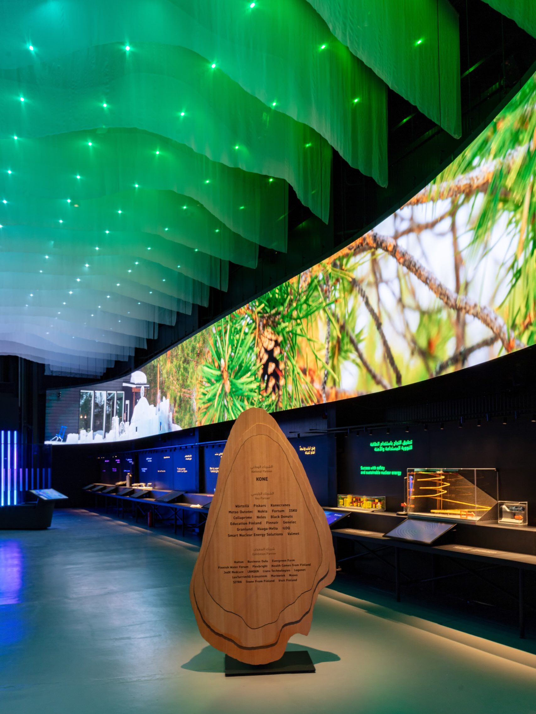 Close-up of the pavilion’s draped white ceiling above a large video wall showing Finnish nature imagery